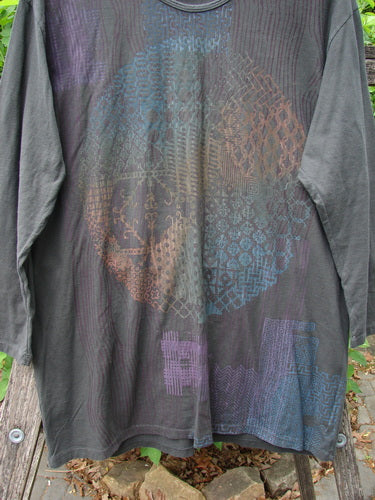 Barclay NWT Long Sleeved Studio Tee Celtic Medallion Smoke Size 0, showcasing a circular geometric pattern in muted rainbow hues, draped over a wooden bench outdoors, highlighting its organic cotton fabric and cozy design.