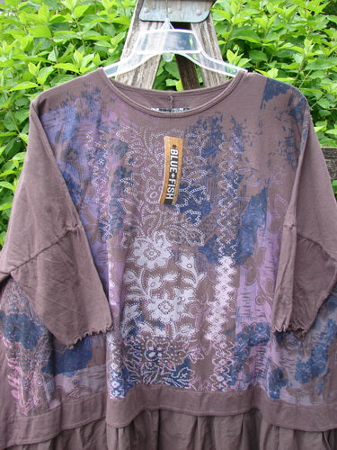 Barclay NWT Batiste Banded Flounce Esperanza Tunic Festive Garden Sparrow OSFA hanging outdoors, featuring patchwork patterns in blue and cream with dolman sleeves and a distinctive flounce hem.