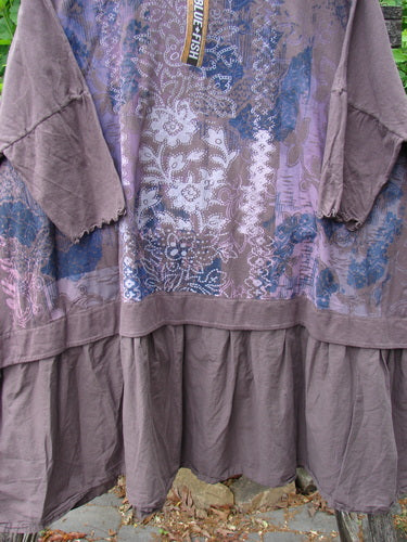 Barclay NWT Batiste Banded Flounce Esperanza Tunic Festive Garden Sparrow OSFA features a loose fit, earthy brown with blue floral prints, three-quarter sleeves, and a gathered tier hem, hanging outdoors.