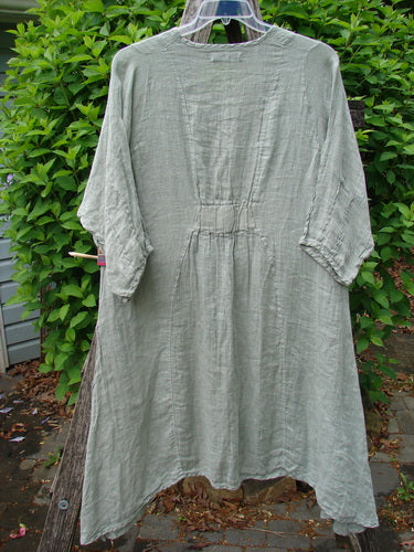 Barclay Linen High Vent Venetian Dress in Sage features a round neckline, three-quarter sleeves, gathered waist, and flared skirt. Hanging outdoors, it showcases the Contour Floral pattern, embodying Bluefishfinder's vintage creative ethos.