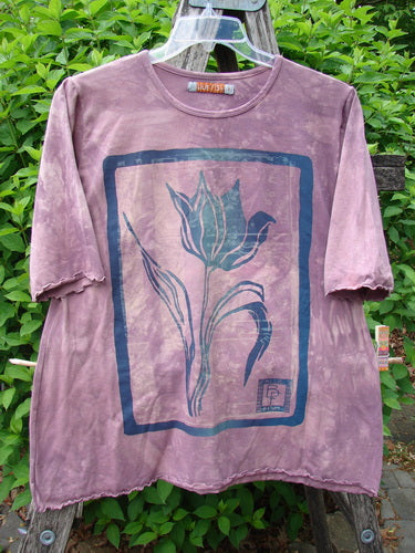 Barclay Cotton Lycra Three Quarter Sleeved Cafe Tee Single Tulip Mottled Mauve Size 1, featuring a stylized flower and bird print, hangs on a stepladder, showcasing its unique design.