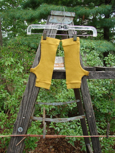 Pair of Barclay NWT Thermal Banded Fingerless Wrist Gloves on a wooden ladder, showcasing the cozy, slightly tapered, and unpainted design with thumbholes and four-finger opening.