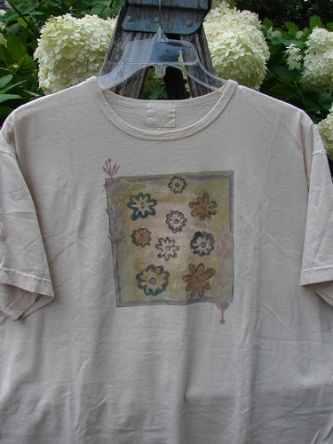 Bluefishfinder.com 1999 Short Sleeved Tee Flower Tops Natural Size 1 in a soft natural beige, with a relaxed crew neck and short sleeves. A faded square floral graphic sits centered on the front, giving the cotton tee a worn, vintage look.