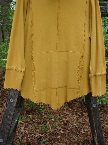 Barclay Thermal Reverse Stitch Tunnel Pocket Top in Mustard on a Wooden Rack, featuring a Curly Edged Floppy Turtleneck and Center Front Kangaroo Pocket.