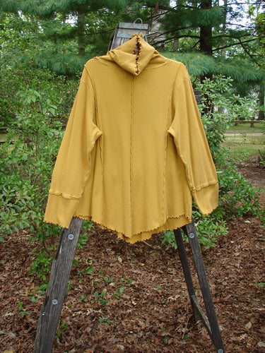 Barclay Thermal Reverse Stitch Tunnel Pocket Top displayed on a wooden stand, showcasing its unique drape, cowl neck, kangaroo pocket, and exterior stitched seams.