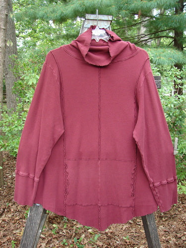 Barclay Thermal Reverse Stitch Tunnel Pocket Top Unpainted Burgundy Size 2 displayed on a wooden pole, showcasing its unique cut, hourglass shape, and center front drop kangaroo tunnel pocket.