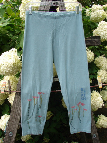Bluefishfinder.com Barclay Cotton Lycra Crop Legging Rising Floral Sky Size 0 in pale blue cotton-lycra, shown front-facing with a cropped straight leg and smooth elastic waistband. Delicate floral stems rise near the hems, with vertical Bluefish text at one ankle.