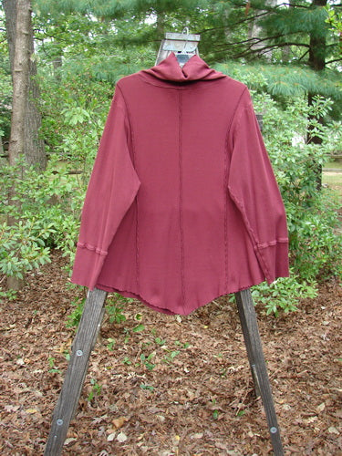 Barclay Thermal Reverse Stitch Tunnel Pocket Top displayed on a wooden stand, showcasing its unique cut, curly-edged turtleneck, and center front drop kangaroo pocket in a stretchy cotton thermal fabric.