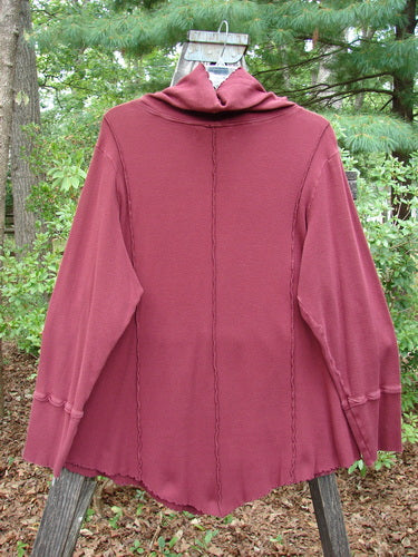 Barclay Thermal Reverse Stitch Tunnel Pocket Top Unpainted Burgundy Size 2 displayed on a wooden pole, showcasing its floppy turtleneck, kangaroo pocket, and unique drape with exterior stitched seams.