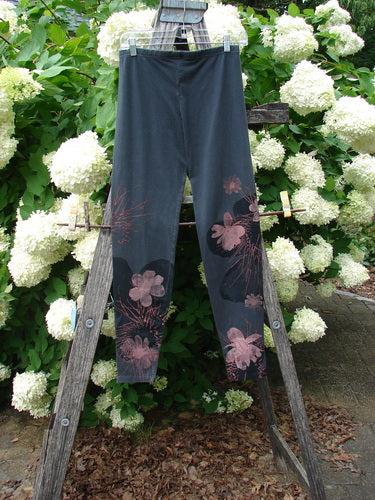 Bluefishfinder.com Barclay Cotton Lycra Legging Daisy Twig Off Black Size 0, shown as slim off-black leggings with pink daisy-twig floral prints on the lower legs and a smooth stretch cotton-lycra finish, hanging from a wooden ladder amid white hydrangeas.