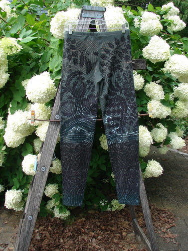 Daisy Hagey Barclay NWT Cotton Lycra Heavy Weight Legging Night Spin Boreal, size 1, in dark gray and black patterned fabric, hanging on a wooden ladder outdoors beside white hydrangeas.