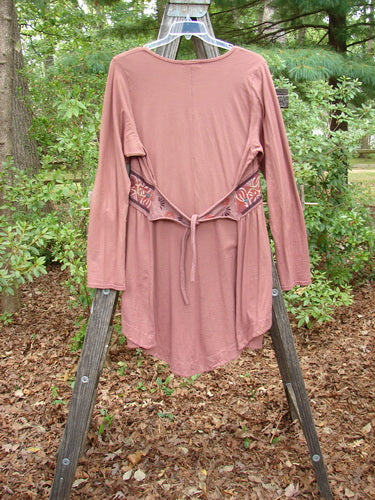 Barclay Decora Banded V Neck Dress Rouge Size 1 displayed on a wooden rack, featuring a deep V neckline, vertical pleats, sectional panels, and a varying hemline.