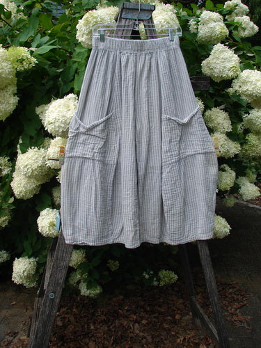 Bluefishfinder.com Barclay Gauze Crop Mojo Pant in unpainted sandy stripe, size 0, shown as airy gray-and-white cropped pants with a softly crinkled gauze texture, elastic waist, and oversized side cargo pockets. The loose silhouette hangs from a wooden ladder against white hydrangeas and green foliage.