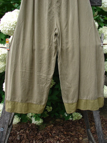 Bluefishfinder.com Barclay lyocell flutter bottom wide-leg pant in unpainted yellow olive, size 0, shown with a soft drape, wide legs, and fluttered hems. The muted olive fabric has a smooth, lightweight texture and hangs against a leafy outdoor backdrop.