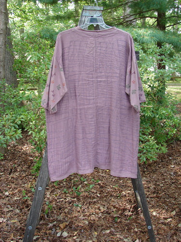 Barclay Linen Cotton Sleeve Pocket Cardigan Rich Mauve Size 0 displayed on a wooden stand, showcasing its curved front, deeper V neckline, floral-themed organic cotton sleeves, and lower squared pockets.
