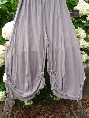 Bluefishfinder.com Barclay Crop Tie Bottom Crop 4 Square Pant in unpainted plum cloud, size 0, shown as loose, draped cropped pants with tie-bottom hems, soft matte fabric, and a pale gray-lilac tone against leafy greenery.