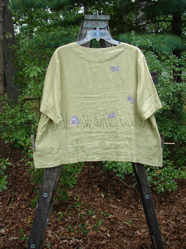 1999 Cabana Top Butterfly Grass Citron Size 2 displayed on a hanger, showcasing shell buttons, a drop pocket, double-paneled lower fabric, and butterfly-themed painted design.