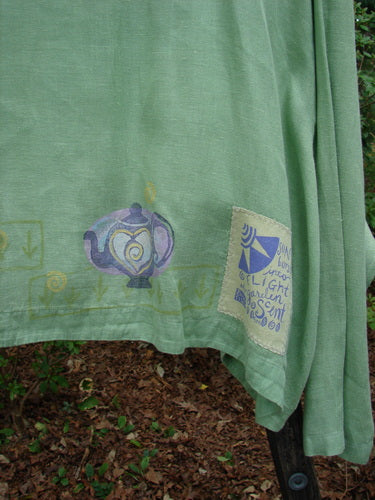 1999 Weathervane Jacket Tea Heart Spearmint Size 2 displayed on a cloth, featuring unique front buttons, an inward rounded side hem, a deeper V neckline, and tea and heart-themed paint.