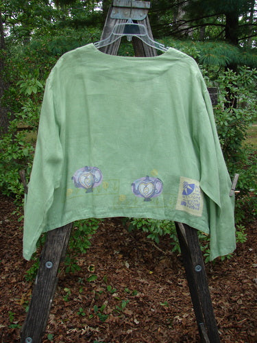 1999 Weathervane Jacket Tea Heart Spearmint Size 2 displayed on a wooden bench swing, featuring unique front mix-match buttons, inward rounded side hem, and deeper V-shaped neckline with tea and heart theme paint.