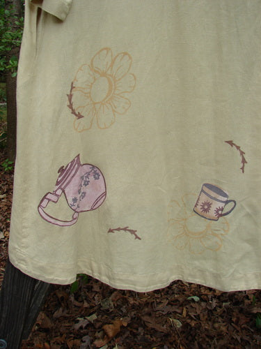 1999 Cream and Sugar Coat Pitcher Plantain OSFA with teapot and teacup design on medium weight linen, featuring a V neckline, oversized shell button, deep side pockets, and upward scoop front hem.