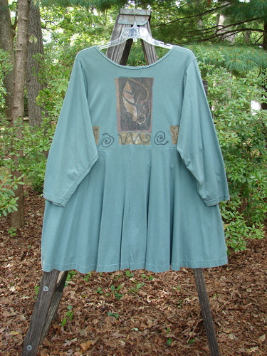 1994 Juniper Dress Swirl Leaf Sea Journey Size 2, displayed on a swing, featuring a wide rounded collar, recycled paper button closures, and a sweeping hemline with vintage swirl and leaf designs.