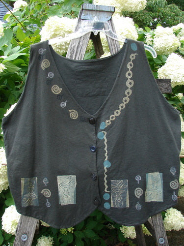 Bluefishfinder.com 1993 The Vest Dancer Black Sand Size 2, a dark sleeveless vest with a soft drape, V-neckline, and front button closure. Spiral and chain-like motifs, plus small rectangular printed panels, add muted blue and tan detail against the black fabric.