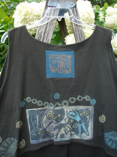 Bluefishfinder.com 1993 The Vest Dancer in black sand, size 2, shown as a sleeveless vest with a soft drape and a wide scoop neckline. The dark fabric carries blue and multicolor graphic patches across the chest and hem, creating a layered, artsy look.