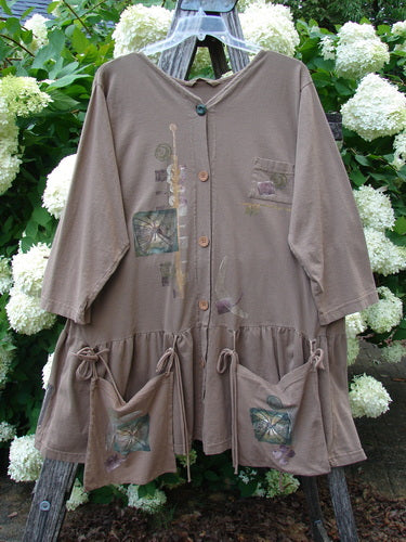 Bluefishfinder.com 1995 Clothespin Jacket Butterfly Mudpie OSFA, a taupe-brown cloth jacket with a V-neck, button front, and patchwork butterfly motifs. It hangs open on a clear hanger, with gathered lower panels and tie details against white hydrangeas and green foliage.