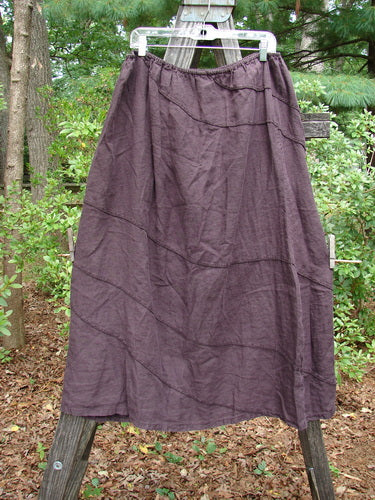 Barclay Linen Hemp Diagonal Skirt Unpainted Eggplant Size 2 displayed on a wooden pole, featuring exterior diagonal stitchery with a slightly shorter length.