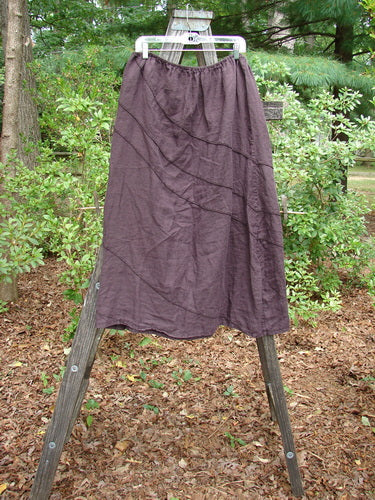 Barclay Linen Hemp Diagonal Skirt Unpainted Eggplant Size 2 displayed on a wooden stand, showcasing its woven texture and diagonal stitching in an outdoor setting.