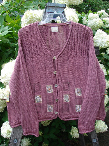 Bluefishfinder.com 1999 Triangle Cardigan Sweater in Pitcher Clay, size 1, shown as a mauve knit cardigan with a deep V-neck, ribbed texture, and button front. Small patterned patch details decorate the lower body, while the sleeves and hem fall in a soft, relaxed drape.