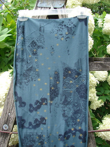 Bluefishfinder.com Barclay Diagional Scarf Wrap Stary Night Garden Blue Hunter OSFA, a long blue wrap scarf with a diagonal drape and layered botanical print in navy, teal, and gold. The lightweight fabric hangs in a narrow vertical panel, its soft woven texture and painterly pattern standing out against the outdoor greenery.