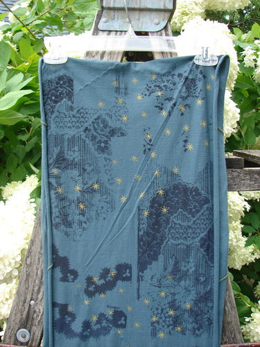 Bluefishfinder.com Barclay Diagional Scarf Wrap Stary Night Garden Blue Hunter OSFA, a draped blue wrap with a soft woven texture, dark floral-and-lace patterning, and scattered gold star motifs. It hangs vertically from clips, filling the frame with layered folds and a cool blue-green palette.