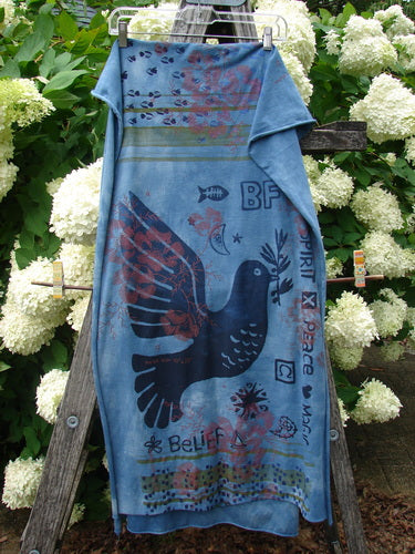 Bluefishfinder.com Barclay Scarf Wrap Belief Spirit Magic Love Dove Echo Blue OSFA in soft blue fabric, printed with a large black dove, layered graphic accents, and scattered words and symbols. The wrap hangs from a hanger against white hydrangeas and greenery, creating a vivid outdoor contrast.