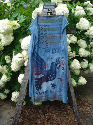 Bluefishfinder.com Barclay Scarf Wrap Belief Spirit Magic Love Dove Echo Blue OSFA in blue, a long lightweight wrap with a soft drape and printed dove, BF lettering, and symbolic motifs. It hangs centered on a wooden ladder among white hydrangeas, with muted daylight and a cool blue-green palette.