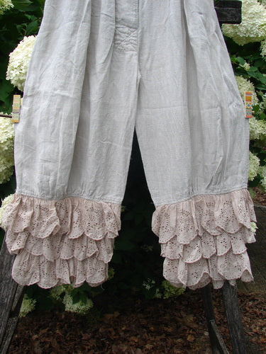 Magnolia Pearl Homespun Linen Ruffle Eyelet Bloomer in natural OSFA, made from softly wrinkled linen with a loose, draped silhouette and layered eyelet ruffles at the hem. The pale neutral fabric falls in front of dark foliage, highlighting the airy texture and gathered detail.