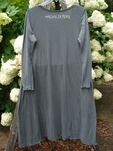 Bluefishfinder.com Magnolia Pearl Cotton Jersey Dylan Dress Fairy Ozzy OSFA in muted gray cotton jersey, a long, loose long-sleeve dress with a softly draped silhouette and raw, slightly uneven hem. The neckline is printed with Magnolia Pearl, and the dress hangs against white hydrangeas and green foliage.