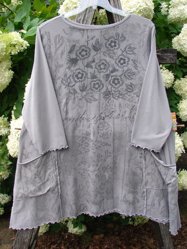 Barclay Cotton Lycra 2 Pocket Urchin Dress Flower Tops Size 0 in soft gray, a loose long-sleeve dress with a sheer floral-print overlay, rounded neckline, scalloped edges, and two front pockets. The lightweight fabric hangs in a relaxed A-line shape.