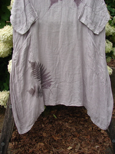 Bluefishfinder.com Barclay Linen Wave Pocket Dress in Fern Rice Paper, a loose linen dress with a soft gray-lavender drape, wide short sleeves, and a fern print near the lower front. The airy fabric hangs in a relaxed A-line shape.