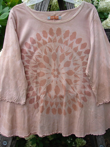 Bluefishfinder.com Barclay Three Quarter Sleeved Cafe Tee in mottled pumpkin, size 1, with a faded giant sunflower graphic centered on the front. The soft, draped tee has three-quarter sleeves, a scoop neckline, and pinked hems, shown against leafy greenery.