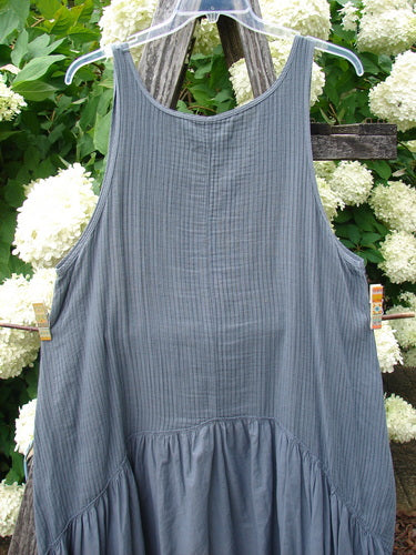 Bluefishfinder.com Barclay Gauze Batiste Summer Frock Jumper in unpainted gray day stripe, size 0, with a sleeveless scoop neck, fine gauzy texture, and gathered lower panel. The dress hangs on a clear hanger against white hydrangeas and weathered wood, in soft natural light.