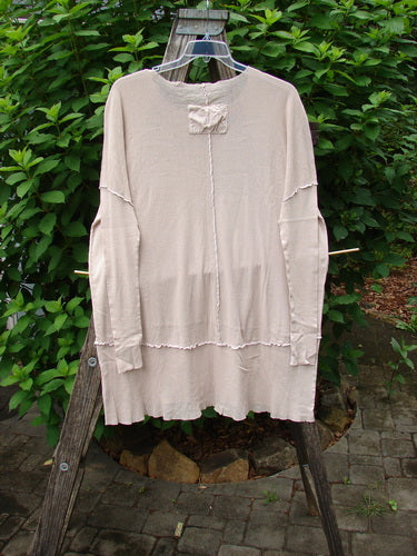 Barclay Cotton Mesh Exterior Stitch Sectional Overtop Unpainted Cloud Size 2 draped on a wooden ladder, showcasing its relaxed tunic style, raw-edge seams, and varying hemline in a garden setting.