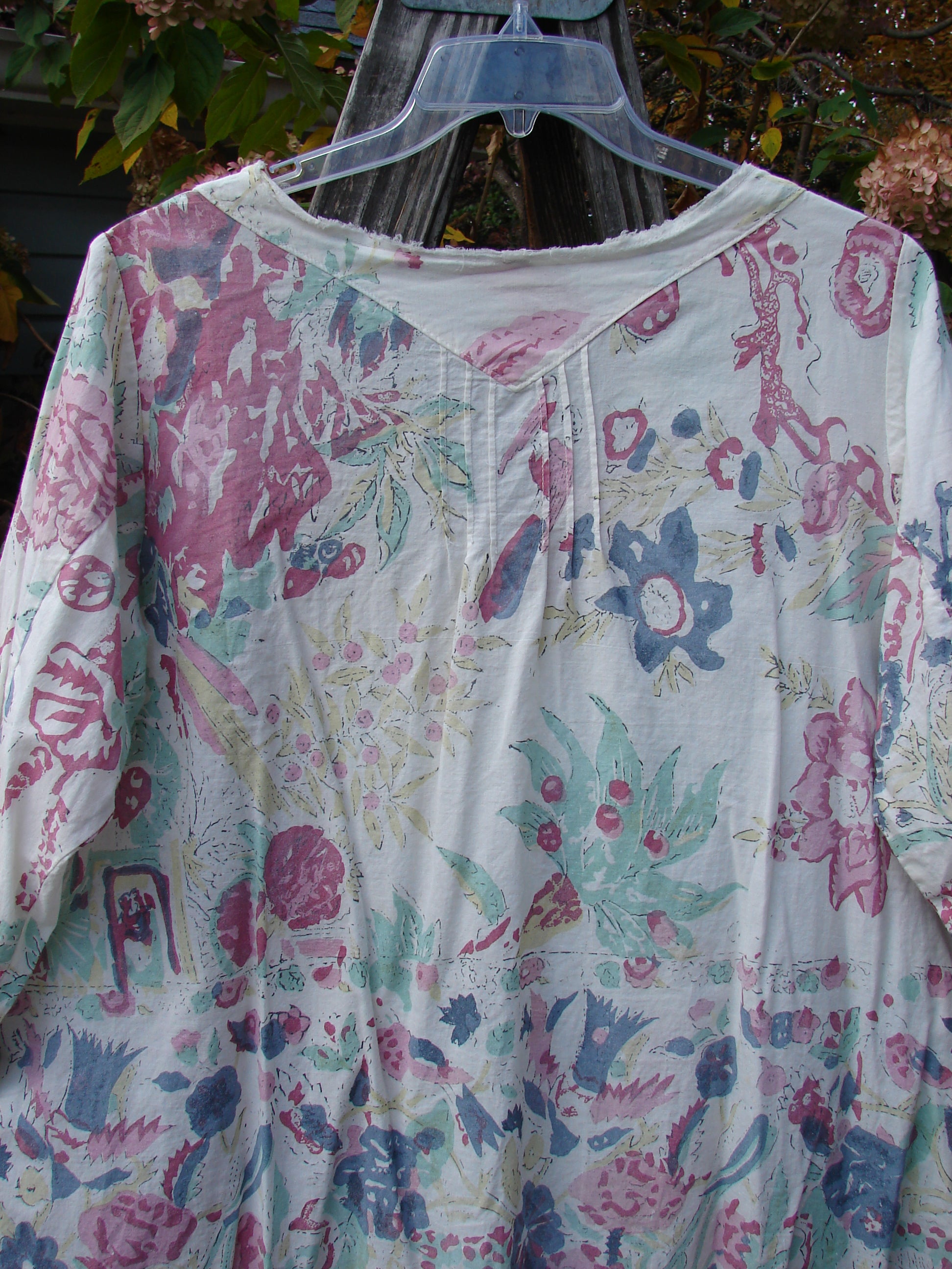 Magnolia Pearl European Cotton Breeze Blouse Spring Florals OSFA, featuring a lightweight linen cotton blend with floral patterns, vertical pleats, raw edges, and button cuff accents.