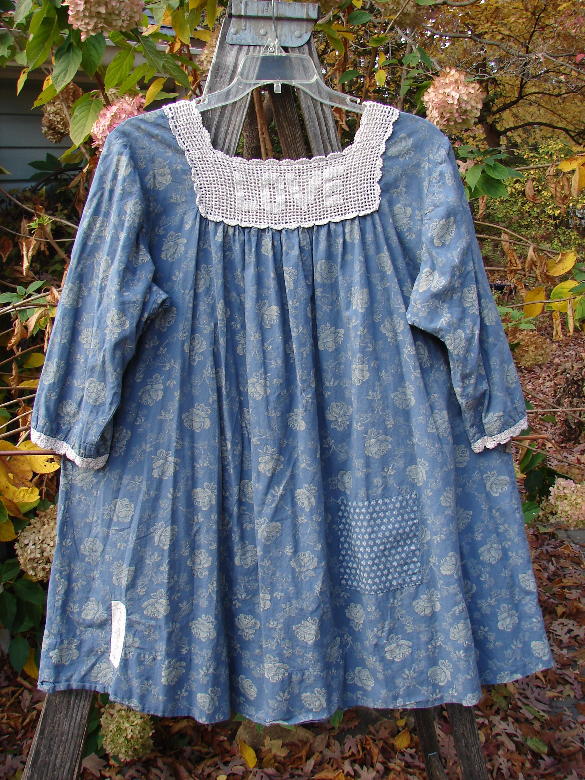 Magnolia Pearl European Cotton Crochet Love Tunic Vintage Blue Rose OSFA on a clothes rack, showcasing a crochet square top, three-quarter sleeves, and floral accents.