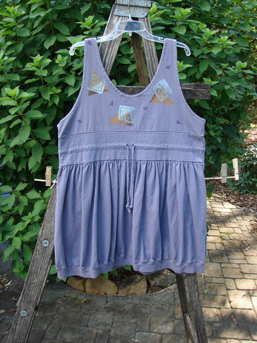 1996 Amusement Jumper Triangle Shadow Mulberry Size 1: A sleeveless tunic with a drawstring waist and geometric triangle motifs, hanging on an outdoor wooden frame, showcasing its vintage style and unique design.