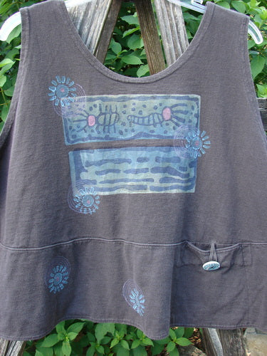 1995 Klee Top Garden Friends Shadow Size 1, featuring a sleeveless, scoop-neck design with hand-painted abstract motifs and a decorative button pocket, displayed on a fence with foliage backdrop.