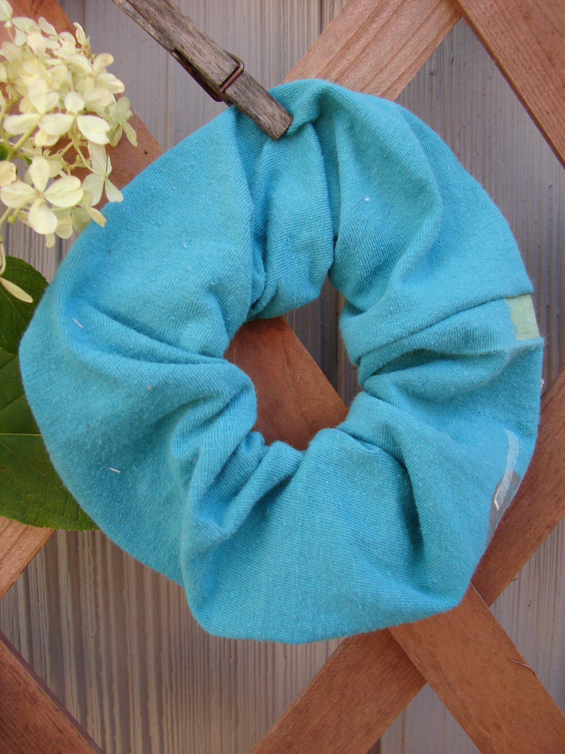 1990 PMU Cotton Hair Scrunchie Abstract Turq One Size displayed on a wooden surface, showcasing its ruffled fabric and thin elastic band, part of Bluefishfinder.com's vintage-inspired sustainable collection.