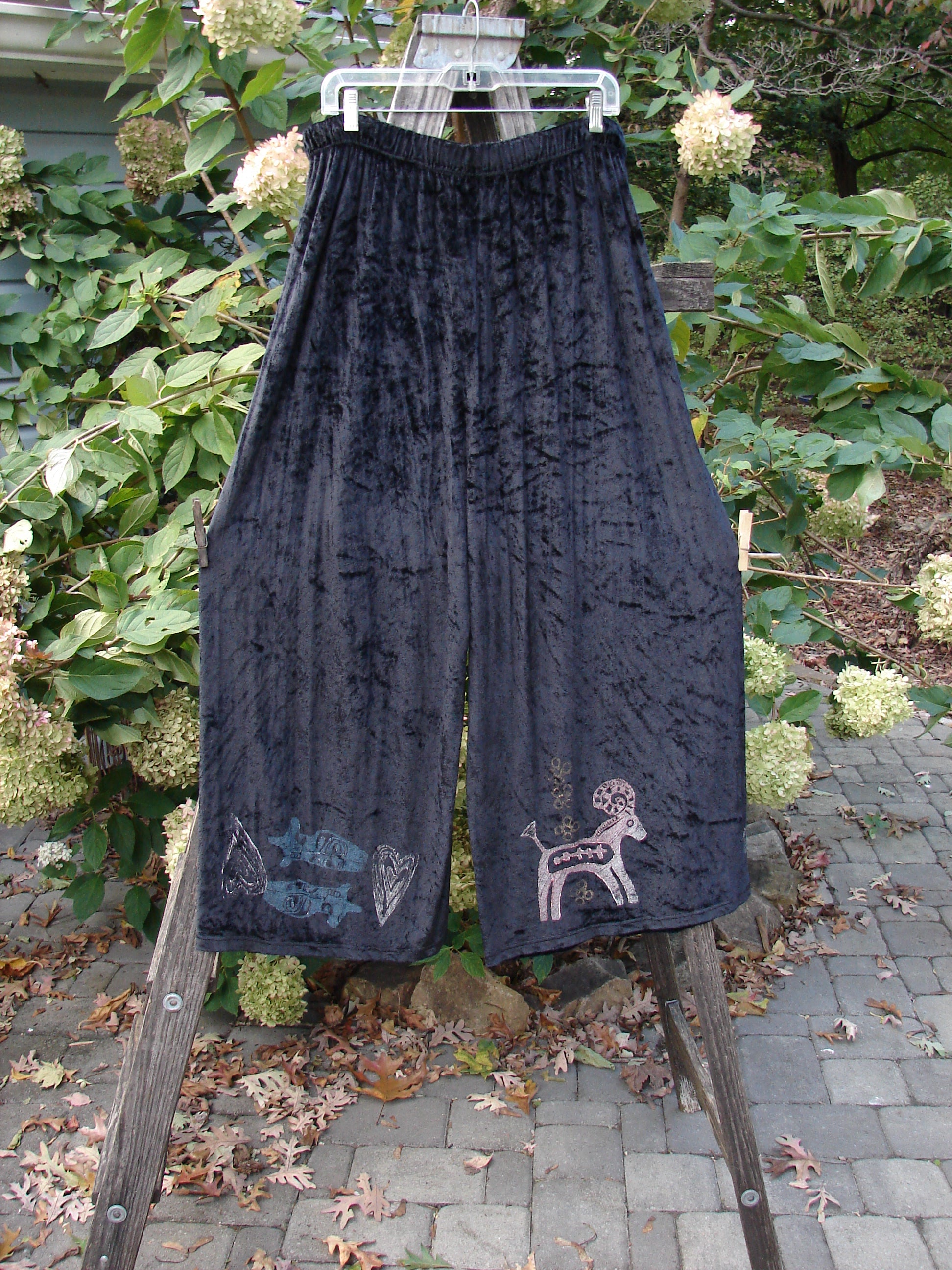 1997 Velvet Cosmos Pant Primitive Ram Obsidian Size 2, featuring a unique deer and goat design, showcased on a fence, highlighting its swingy, pocketless style and elastic waistband.