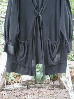 2000 Crepe Rennai Jacket Celtic Black Size 2: A black jacket with front and back ties, pointed hem, and gathered cuffs, hanging on a clothes rack.