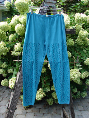 A Barclay Cotton Lycra Bally Layering Pant Legging in Aqua, size 2. Features include a full elastic waistband, slightly narrowing lower, and average length legging. The continuous criss-cross theme paint adds a fun touch. Soft and forgiving feel with the signature Blue Fish patch. Waist relaxed 28, waist fully extended 40, hips 42, inseam 29, length 40 inches.